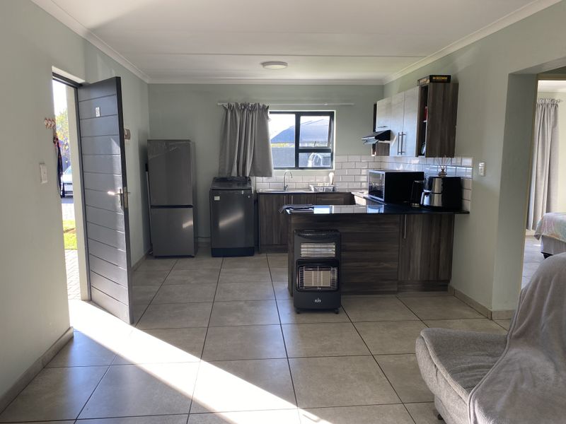 Open-plan kitchen featuring dark wood cabinetry, granite countertops, subway tile backsplash, and tiled flooring, with direct access to the exterior.
