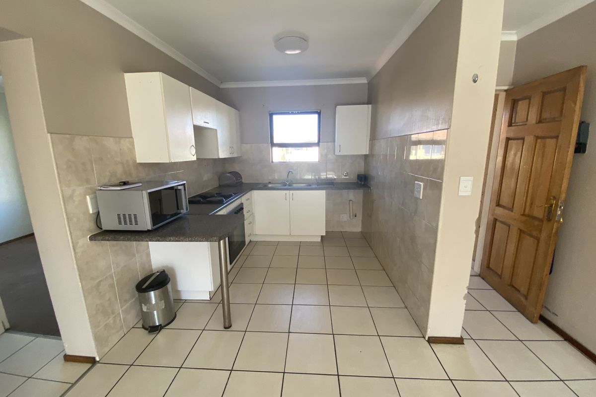 Functional kitchen featuring tiled flooring, built-in cabinetry, a tiled backsplash, and integrated oven and hob, offering a practical layout for daily use.