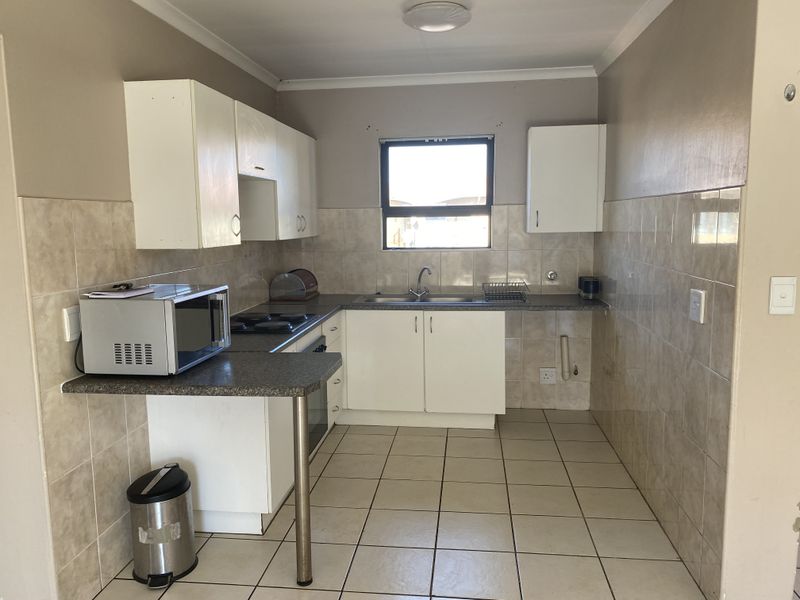 A functional kitchen featuring white cabinetry, laminate countertops, tiled splashbacks, and built-in cooking appliances, offering a blank canvas for modern updates.