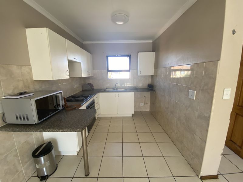 A functional kitchen featuring built-in cabinetry, laminate countertops, ceramic tile backsplash, and tiled flooring, providing a practical space for meal preparation.