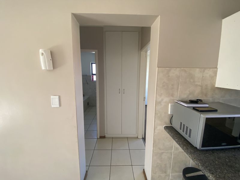 A functional hallway featuring tiled flooring and a built-in cupboard, providing access to adjacent rooms within the apartment.