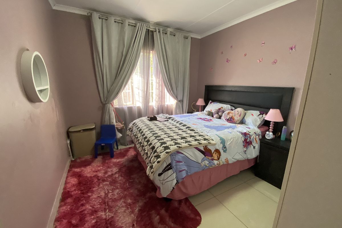 A standard bedroom featuring tiled flooring, coved ceilings, and window treatments, providing a functional space for rest.
