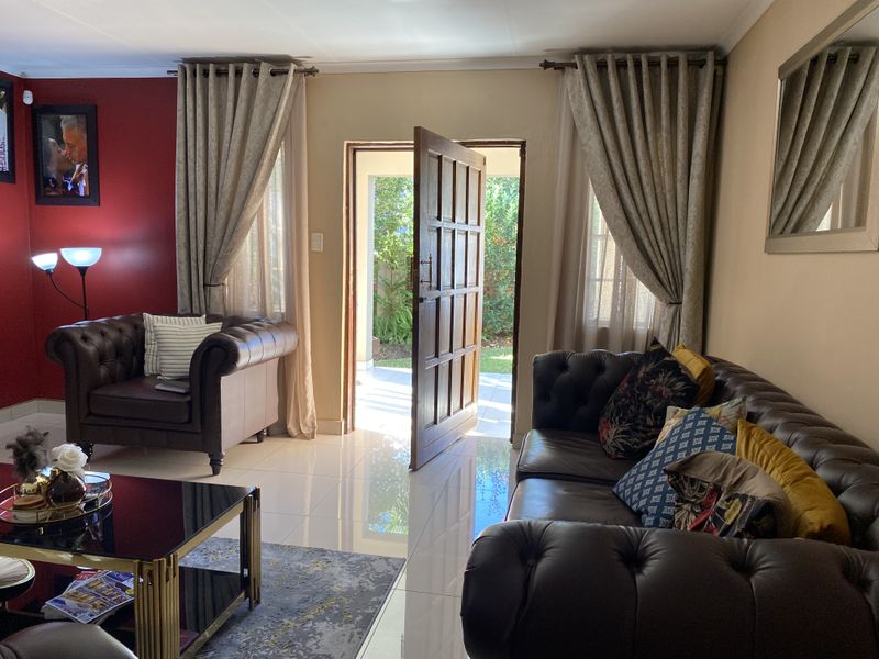 A living room featuring polished tiled flooring and a timber panelled door providing direct access to the outdoor area.