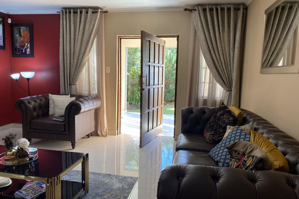 A living room featuring polished tiled flooring and a timber panelled door providing direct access to the outdoor area.