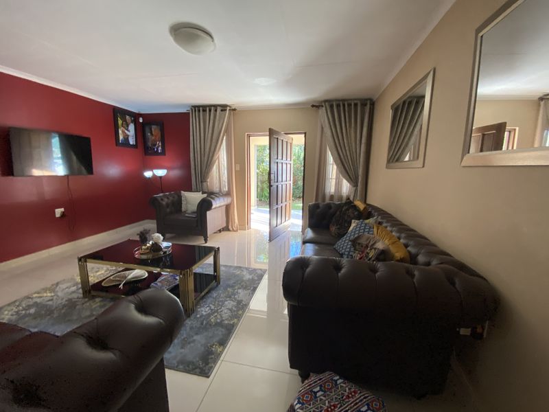 A living room featuring tiled flooring, a red accent wall, and direct access to the exterior through a doorway.