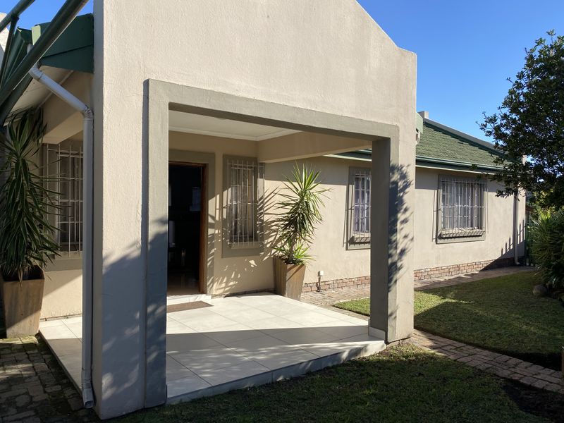 A covered patio area featuring tiled flooring and security bars on the windows, providing a functional outdoor transition space.