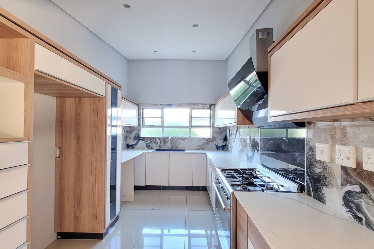 Modern kitchen featuring sleek wood-tone and white cabinetry, stone countertops, gas hob with extractor, and high-quality tiled flooring in a clean, contemporary layout.