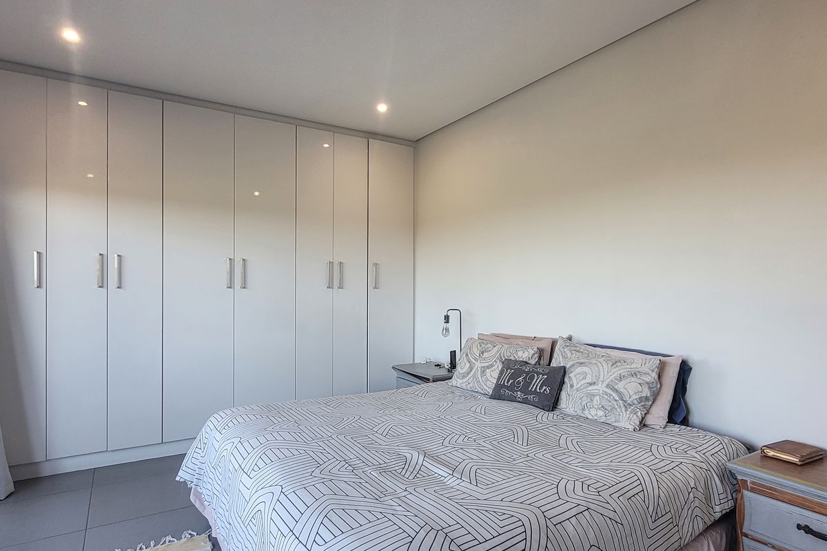 A well-maintained bedroom featuring extensive floor-to-ceiling built-in cabinetry with a modern, clean finish and recessed ceiling lighting.