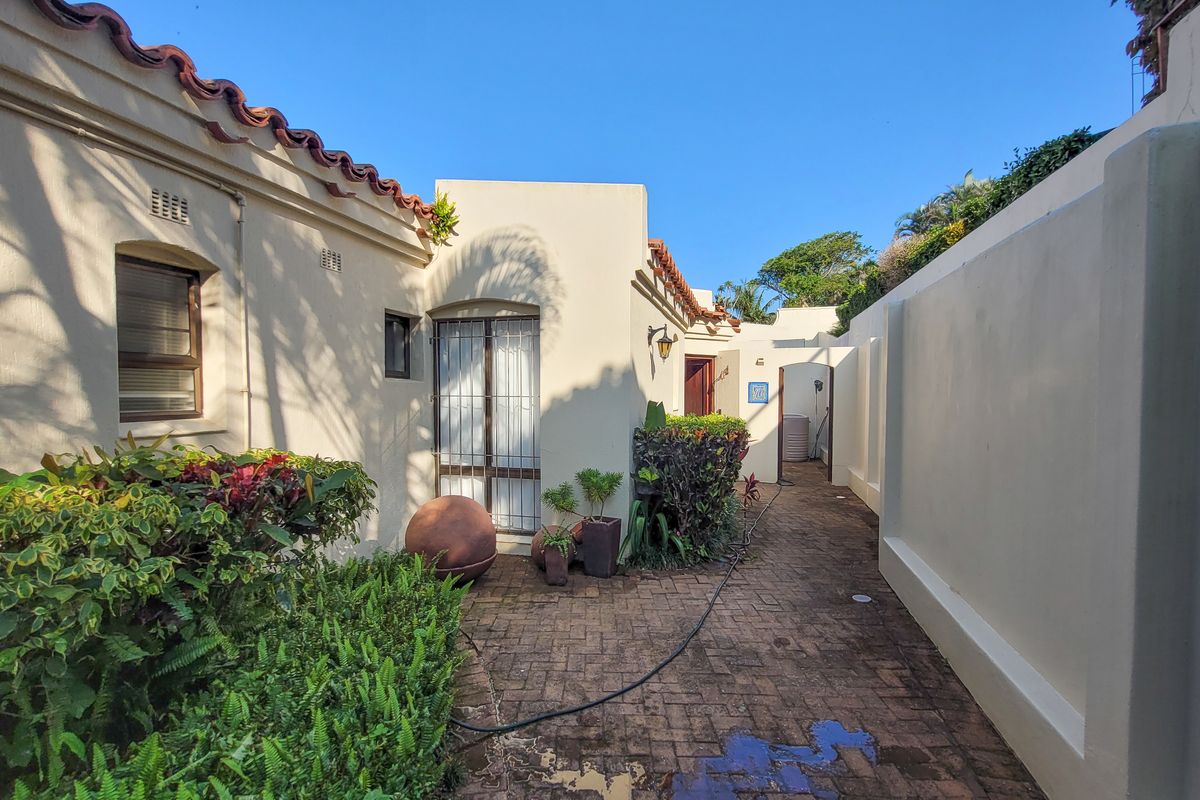 A private rear courtyard featuring paved flooring, established garden beds, and direct access to the townhouse interior.