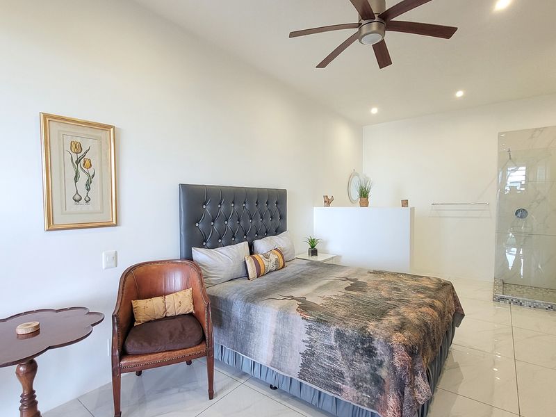 Spacious bedroom featuring modern tiled flooring, recessed lighting, a ceiling fan, built-in wardrobe, and an integrated glass-enclosed shower area.