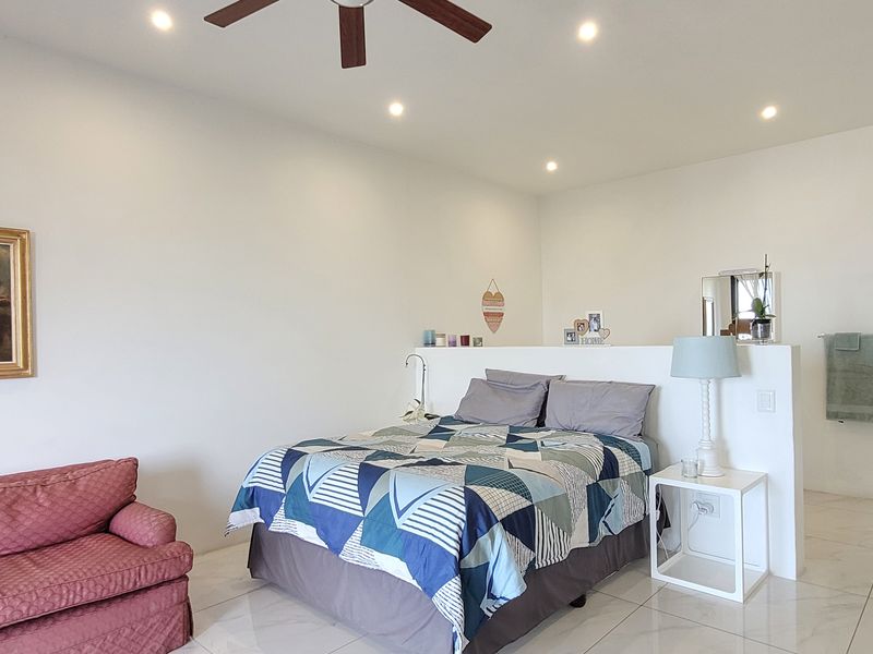 Spacious bedroom featuring tiled flooring, recessed lighting, a ceiling fan, and a functional half-wall partition separating the sleeping area.