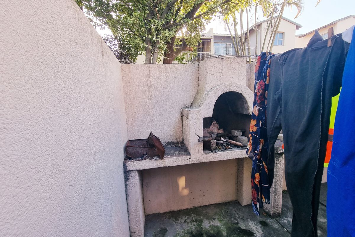 Outdoor area featuring a built-in masonry braai and concrete flooring, situated within a private courtyard setting.