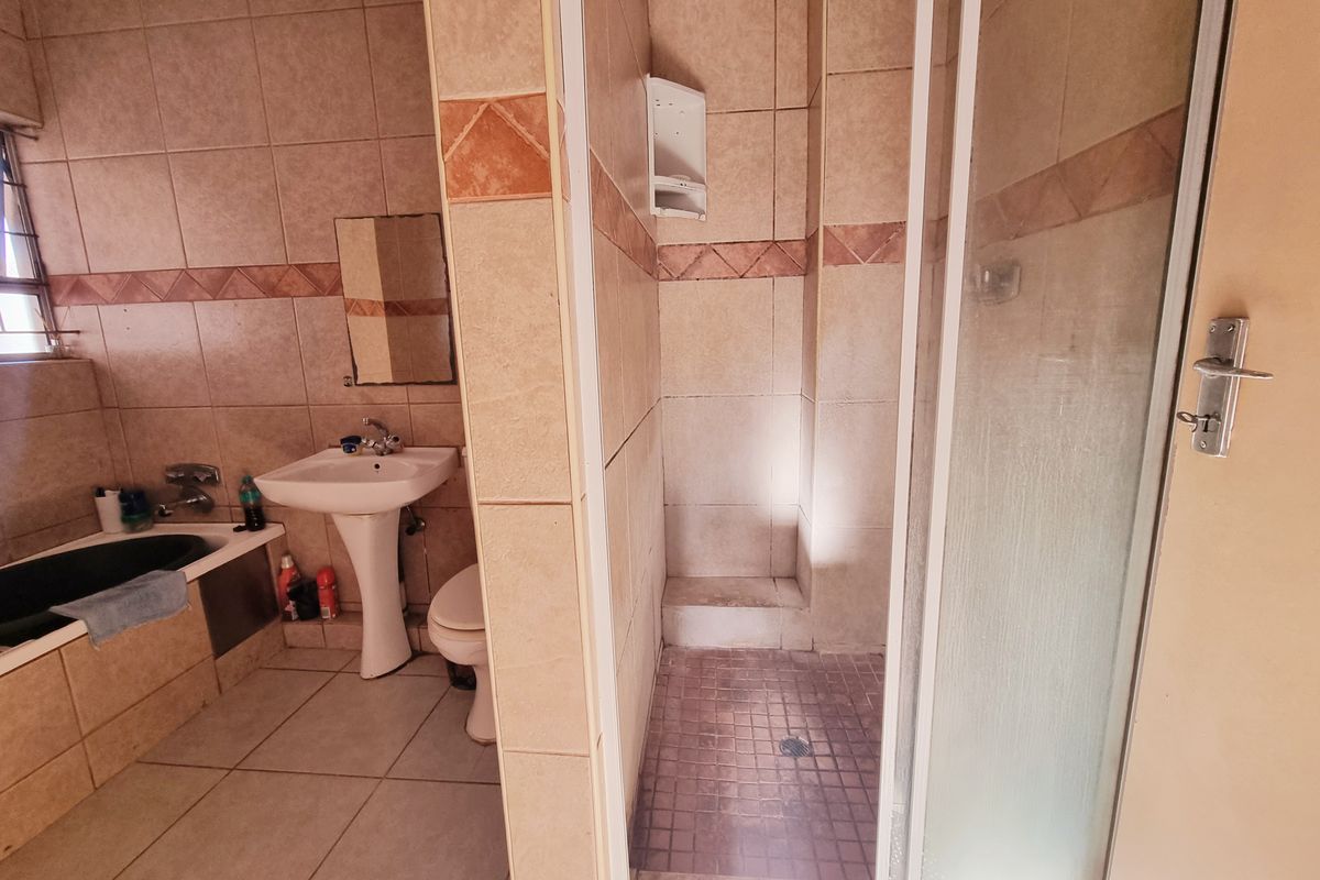 A dated bathroom featuring a tiled shower enclosure, pedestal basin, and a built-in bathtub with tiled surround.