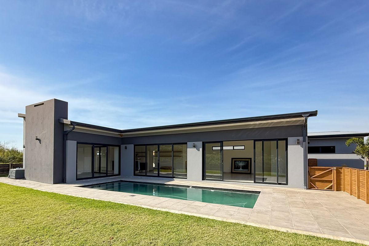 Rear view of a modern townhouse featuring a swimming pool, tiled patio area, and large sliding glass doors leading into the living space.
