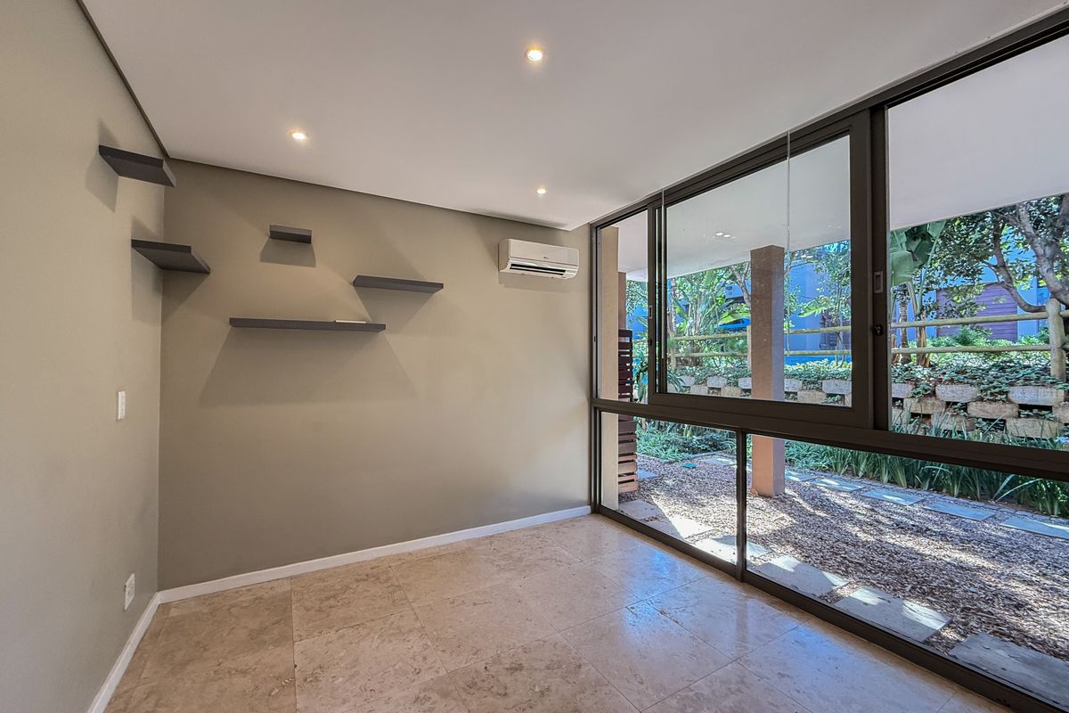 Bright living area featuring stone flooring, recessed lighting, air conditioning, and large sliding glass doors opening to a private garden view.