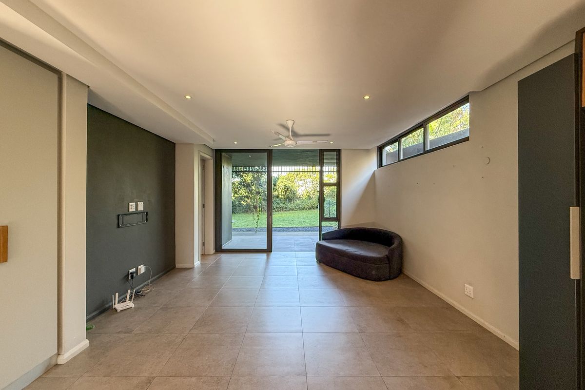 Spacious living area featuring large format floor tiles, recessed lighting, a ceiling fan, and sliding glass doors providing direct access to the outdoor patio.