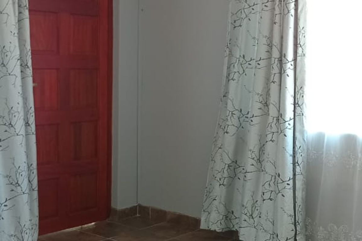 A bedroom featuring tiled flooring, a wall-mounted air conditioning unit, and a solid timber door.