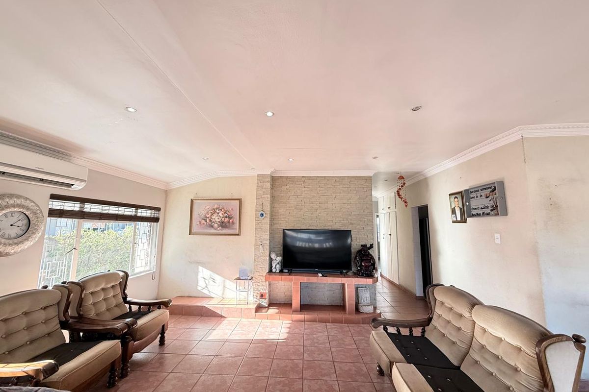 Spacious living room featuring a built-in stone-clad fireplace hearth, tiled flooring, and a wall-mounted air conditioning unit.