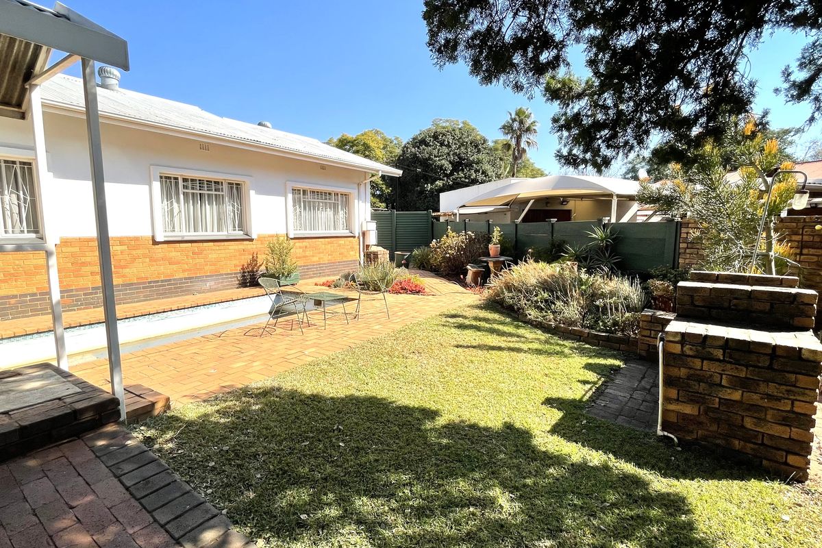 A private rear garden featuring a paved patio area, a built-in brick braai, and a small swimming pool set against the house exterior.