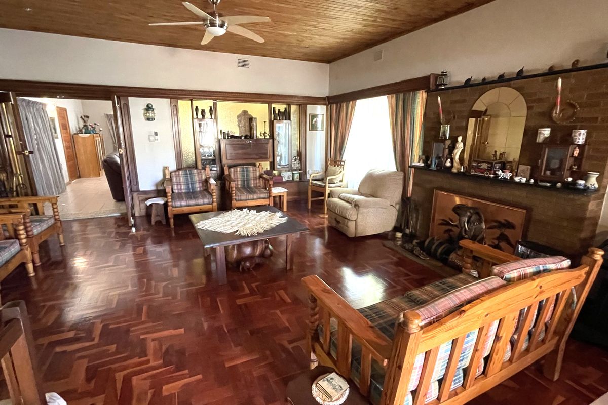 Spacious living room featuring polished parquet timber flooring, a timber-clad ceiling with a ceiling fan, and a prominent brick fireplace.