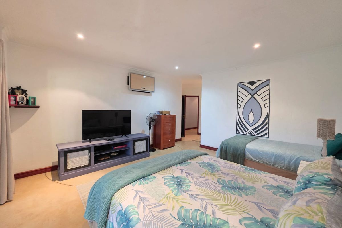 Spacious bedroom featuring recessed ceiling lighting, a wall-mounted air conditioning unit, and tiled flooring.