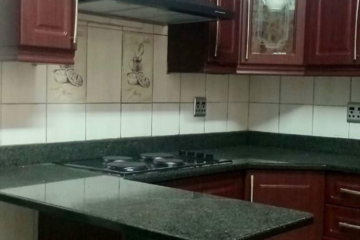A functional kitchen featuring dark wood cabinetry, granite countertops, a breakfast bar, and a built-in extractor fan.