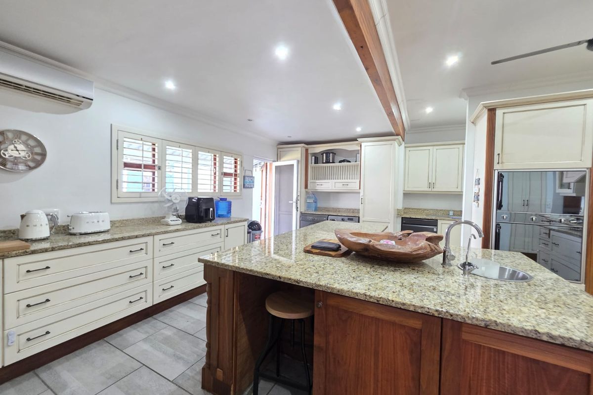 Spacious kitchen featuring granite countertops, a large central island with a prep sink, custom cabinetry, and recessed lighting.