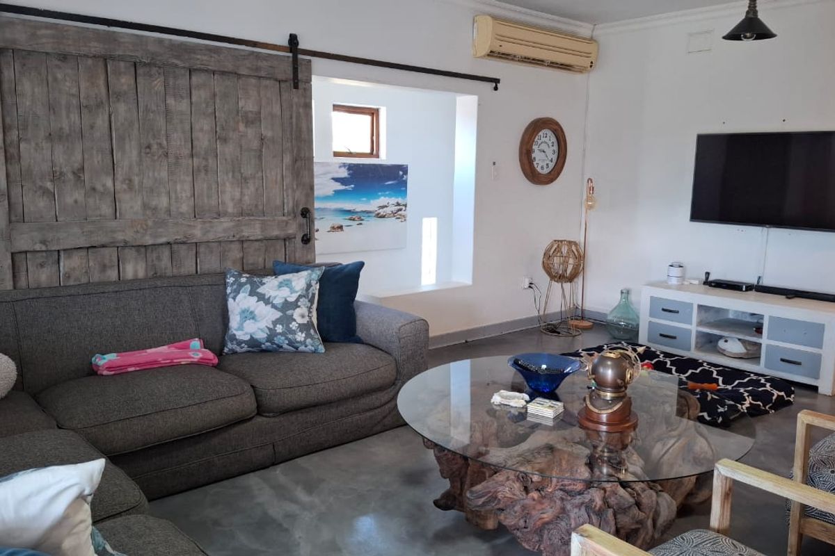 A living room featuring polished concrete floors, a rustic sliding barn door, and a wall-mounted television.