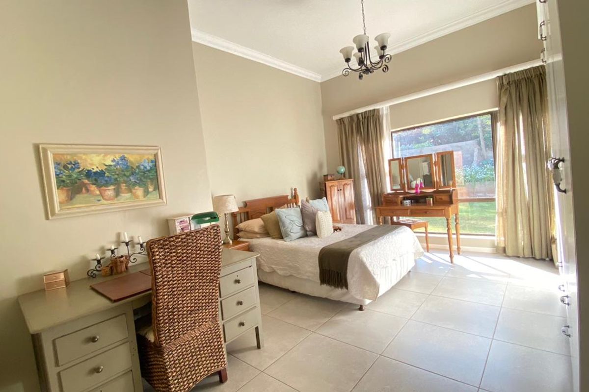 Spacious bedroom featuring large windows, tiled flooring, and crown molding, offering a bright and comfortable living space.