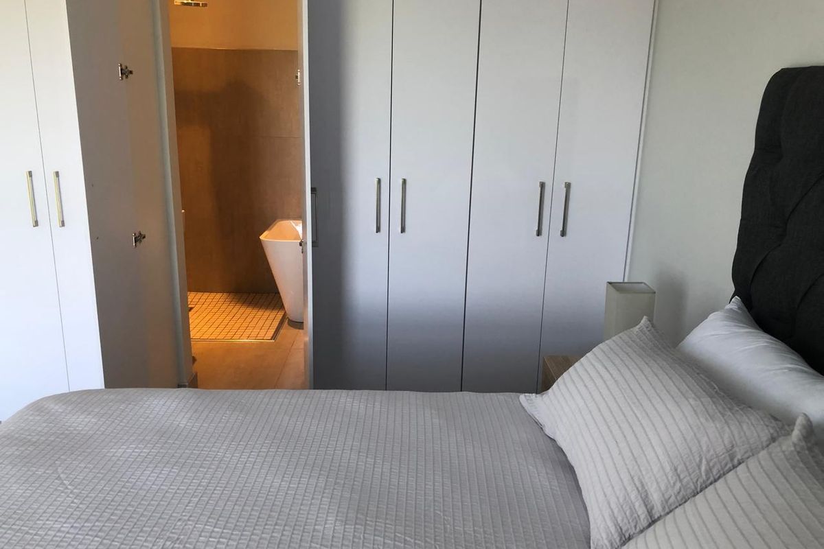 A bedroom featuring built-in wardrobes and an en-suite bathroom with a shower and freestanding bathtub.