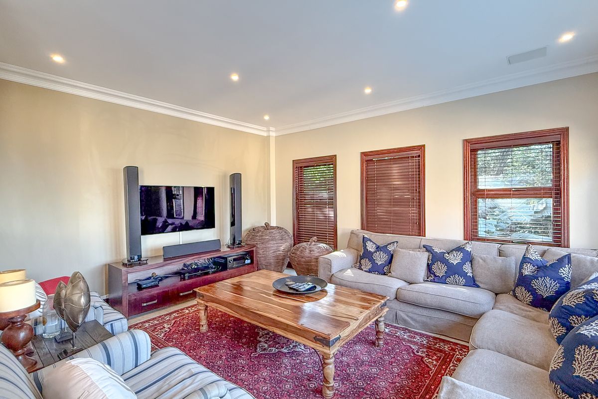 A comfortable living room featuring crown molding, recessed downlighting, and timber-framed windows with venetian blinds.