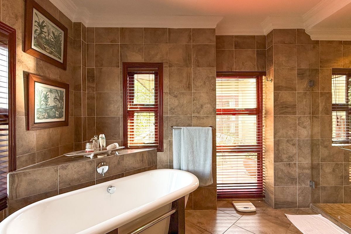 A well-appointed bathroom featuring a modern freestanding bathtub, a spacious walk-in shower, and warm-toned ceramic tiling throughout.