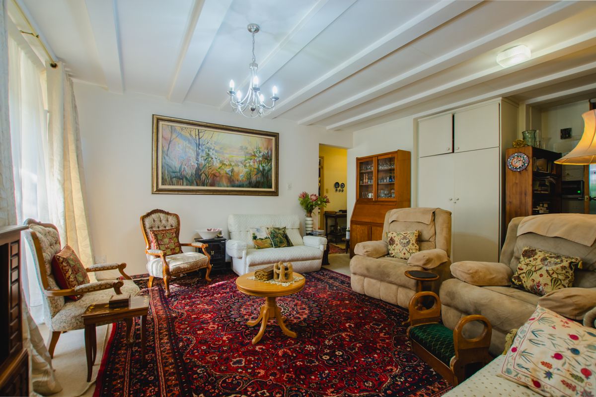 A spacious living room featuring exposed beam ceilings, built-in cabinetry, and large windows allowing for natural light.