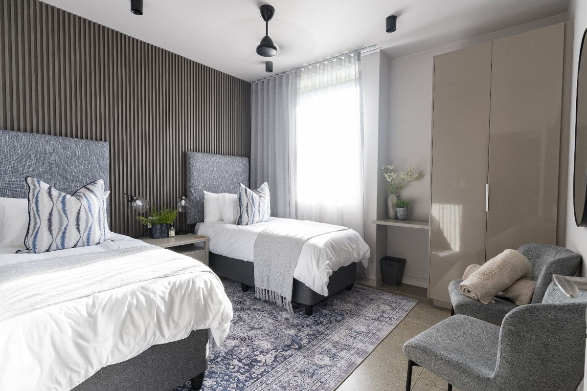 A modern bedroom featuring a textured slat feature wall, built-in wardrobe, and neutral finishes, offering a clean and contemporary living space.