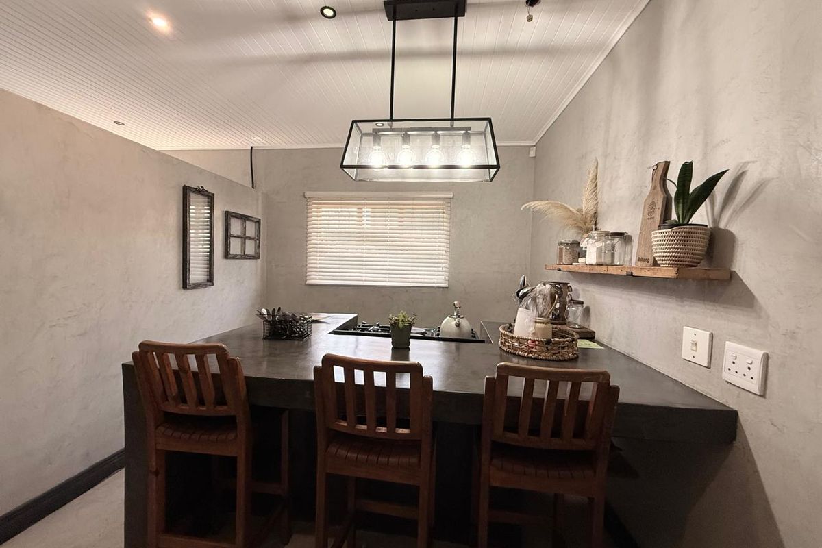 A modern kitchen featuring a large concrete island with a built-in gas hob, complemented by a stylish pendant light and textured grey walls.