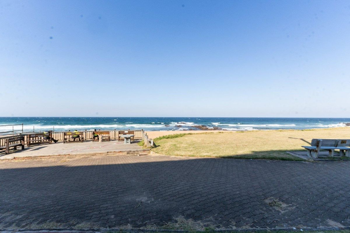 Outdoor area featuring a wooden deck and paved space with direct ocean views and beach access.