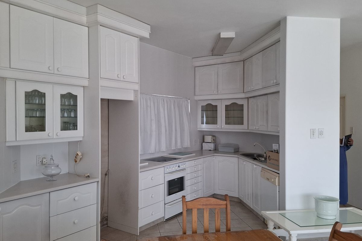 A functional kitchen featuring white cabinetry, built-in oven, hob, and tiled flooring, offering a clean and practical layout for daily meal preparation.