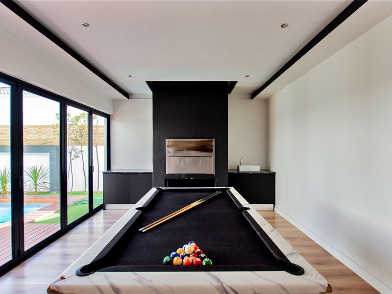 Modern living area featuring a built-in fireplace, sleek cabinetry with a sink, and large sliding glass doors opening to the pool area.