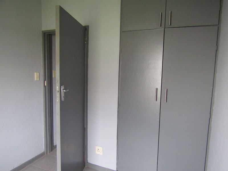 A simple bedroom featuring built-in cupboards, neutral wall finishes, and an internal door, providing a functional and blank canvas space.