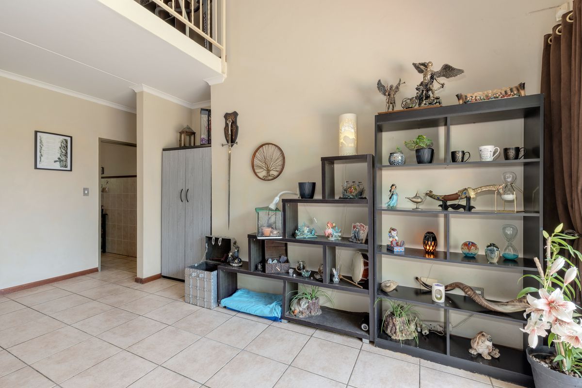 Spacious living area featuring tiled flooring, a mezzanine level with a safety railing, and neutral wall finishes.