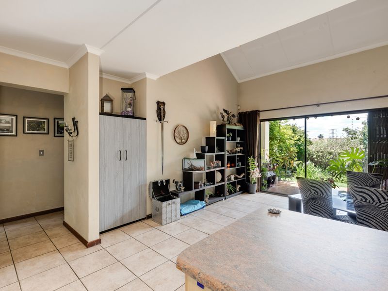 Open plan living area featuring tiled flooring, vaulted ceilings, and large sliding glass doors providing direct access to the garden.