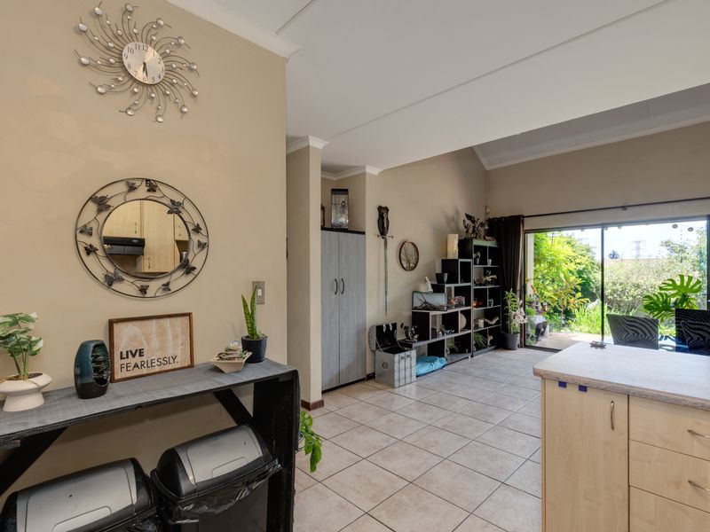 Open plan living area featuring tiled flooring, kitchen cabinetry with laminate countertops, and large sliding glass doors providing access to the garden.