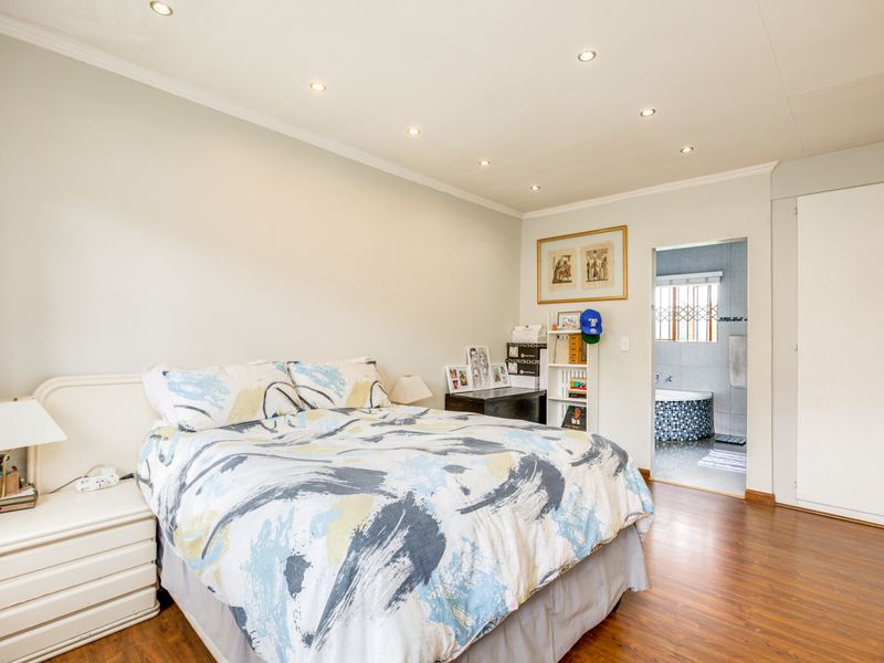 Spacious bedroom featuring laminate flooring, recessed downlighting, and built-in cupboards, with direct access to an en-suite bathroom.