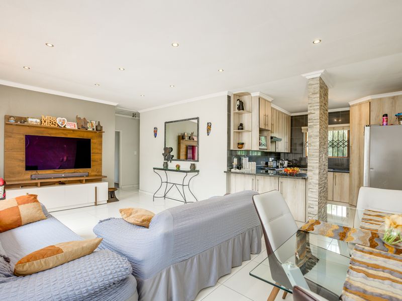 Spacious open-plan living area featuring a modern kitchen with granite countertops, a stone-clad pillar, and a built-in media unit with recessed lighting.