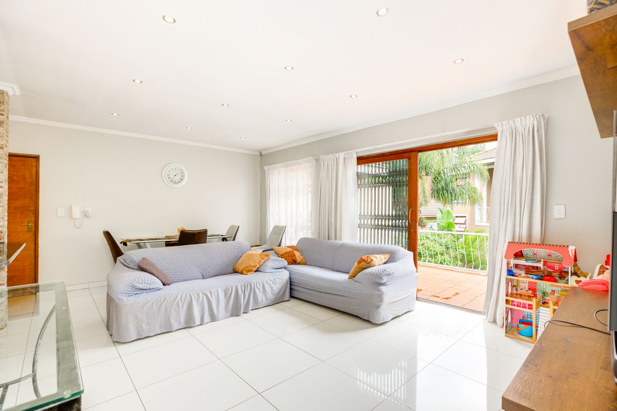 Spacious living room featuring bright tiled flooring, recessed lighting, and a large sliding glass door providing access to an outdoor balcony area.