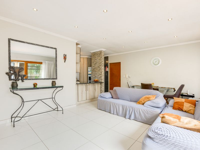 Spacious open-plan living area featuring tiled floors, recessed lighting, and a modern kitchen with stone-cladding accents and built-in cabinetry.