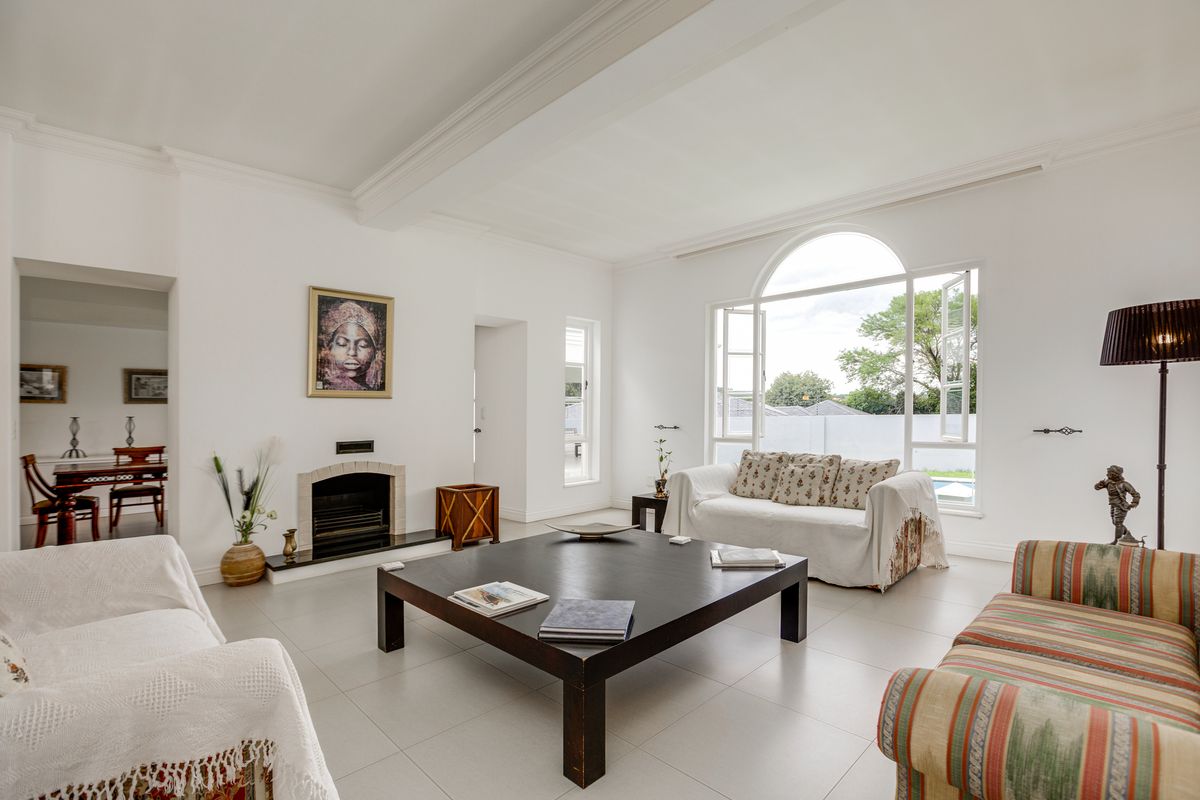 Spacious living room featuring large arched windows, tiled flooring, and a built-in fireplace, offering a bright and airy atmosphere.
