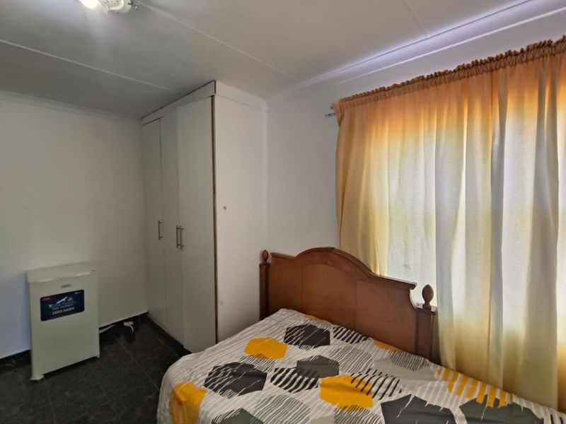 A functional bedroom featuring built-in wardrobe storage and tiled flooring, offering a neutral base for personalization.