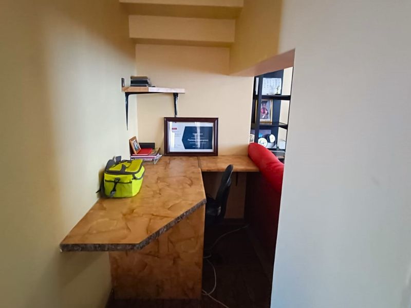 A compact home office nook featuring a built-in corner desk and wall-mounted shelving, providing a functional workspace within the townhouse.