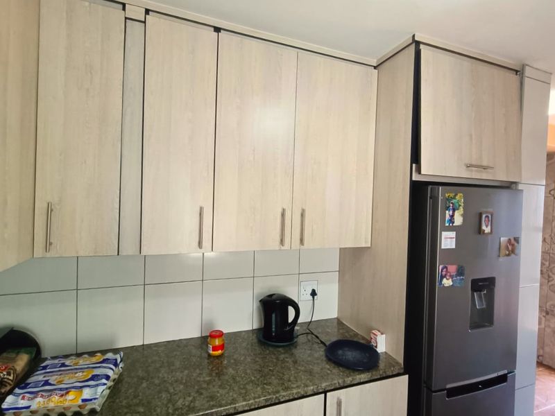 A functional kitchen area featuring light-toned laminate cabinetry, granite countertops, and a tiled backsplash, providing practical storage and workspace.